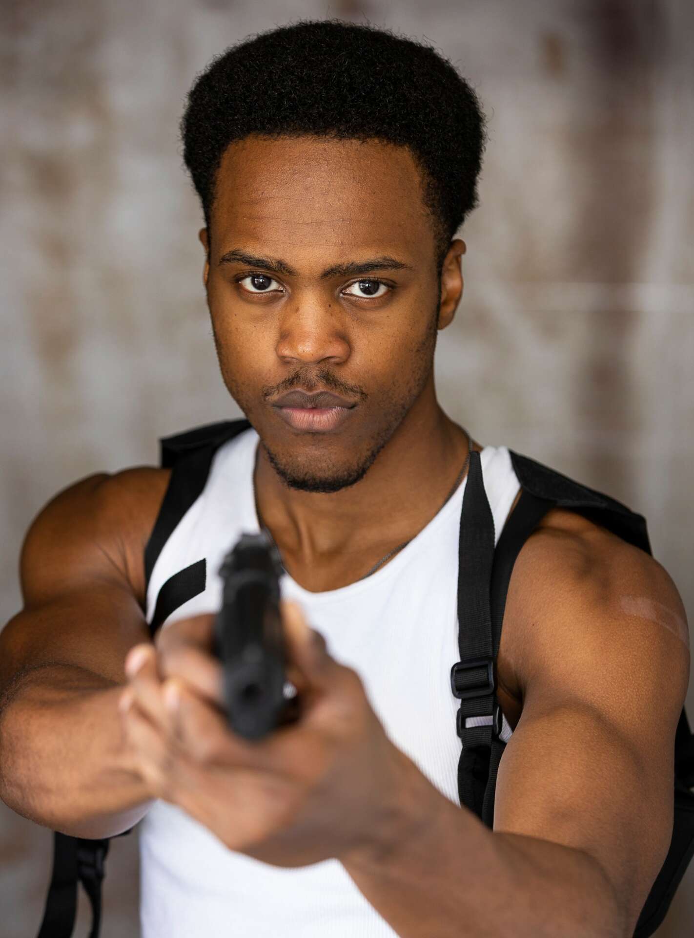 Tash Jordan in a tactical harness aiming a pistol toward the camera