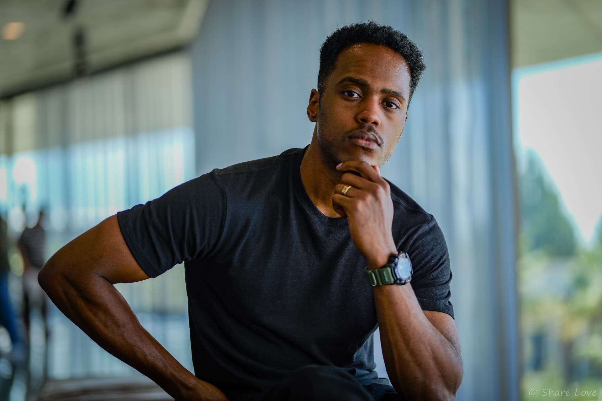 Tash Jordan seated with a hand at his chin