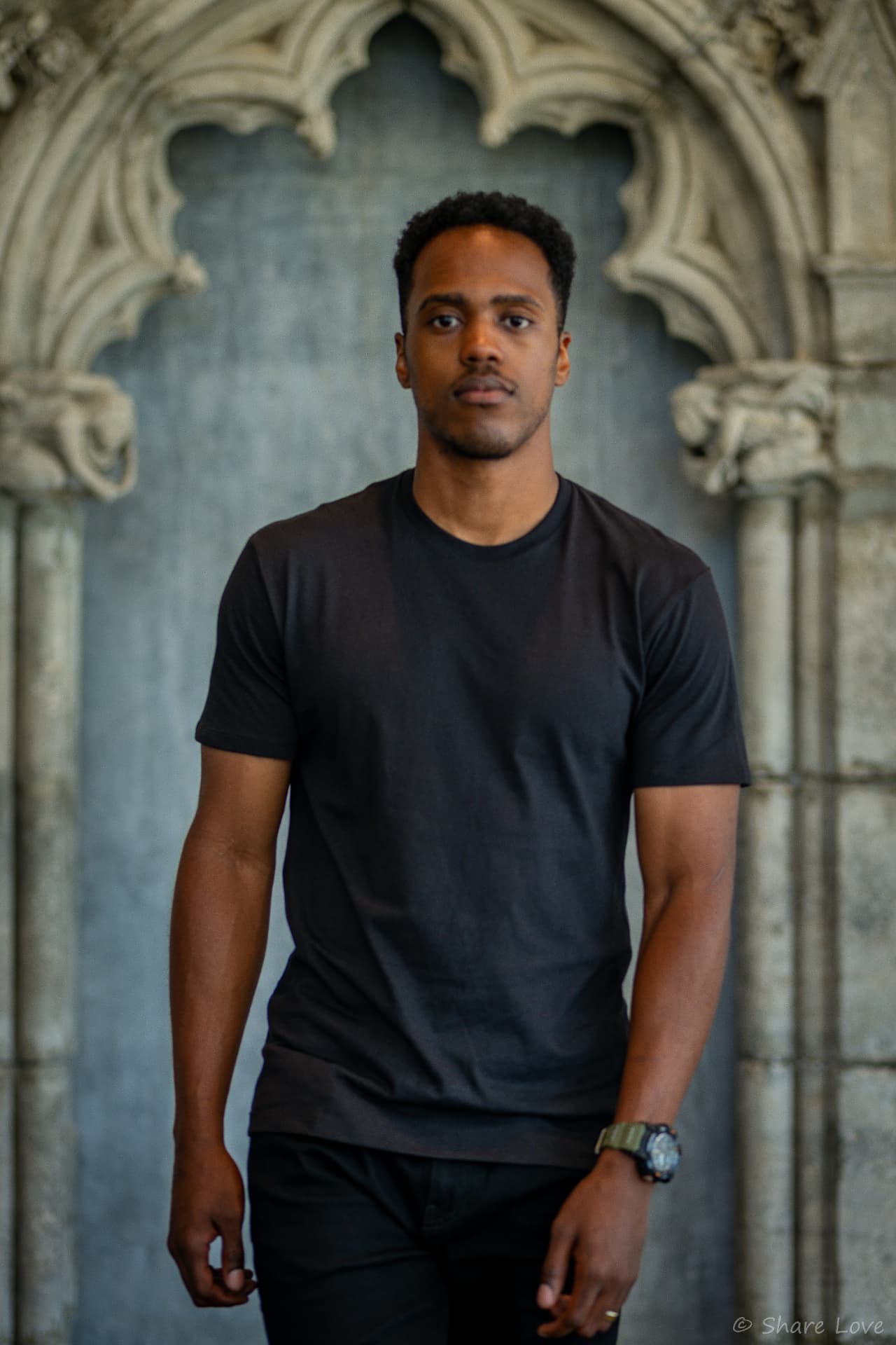 Tash Jordan standing centered under a gothic stone archway